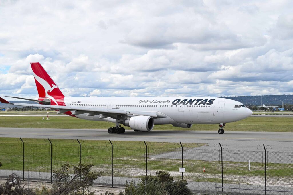A view of Qantas aircraft in airport in background of cloudy sky