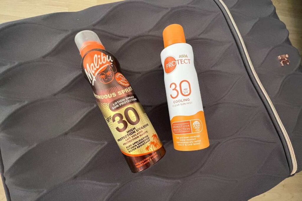 Two can of sun spray on a luggage case